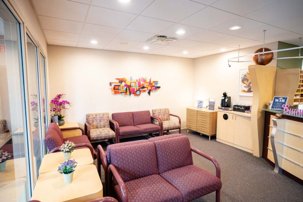 Modern waiting area at Kittleson Orthodontics in Mequon, featuring comfortable seating, colorful wall art, and amenities like complimentary Wi-Fi and beverages, emphasizing a welcoming environment for patients seeking orthodontic care.