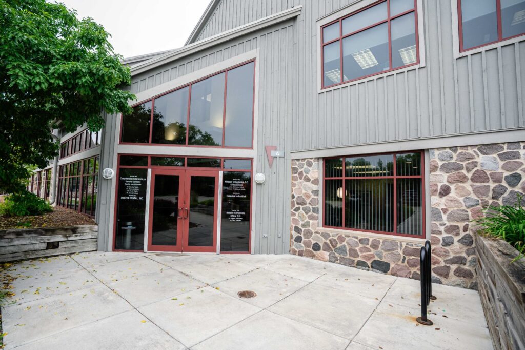 Modern exterior of Kittleson Orthodontics office in Mequon, featuring large windows, stone accents, and clear signage for orthodontic services.
